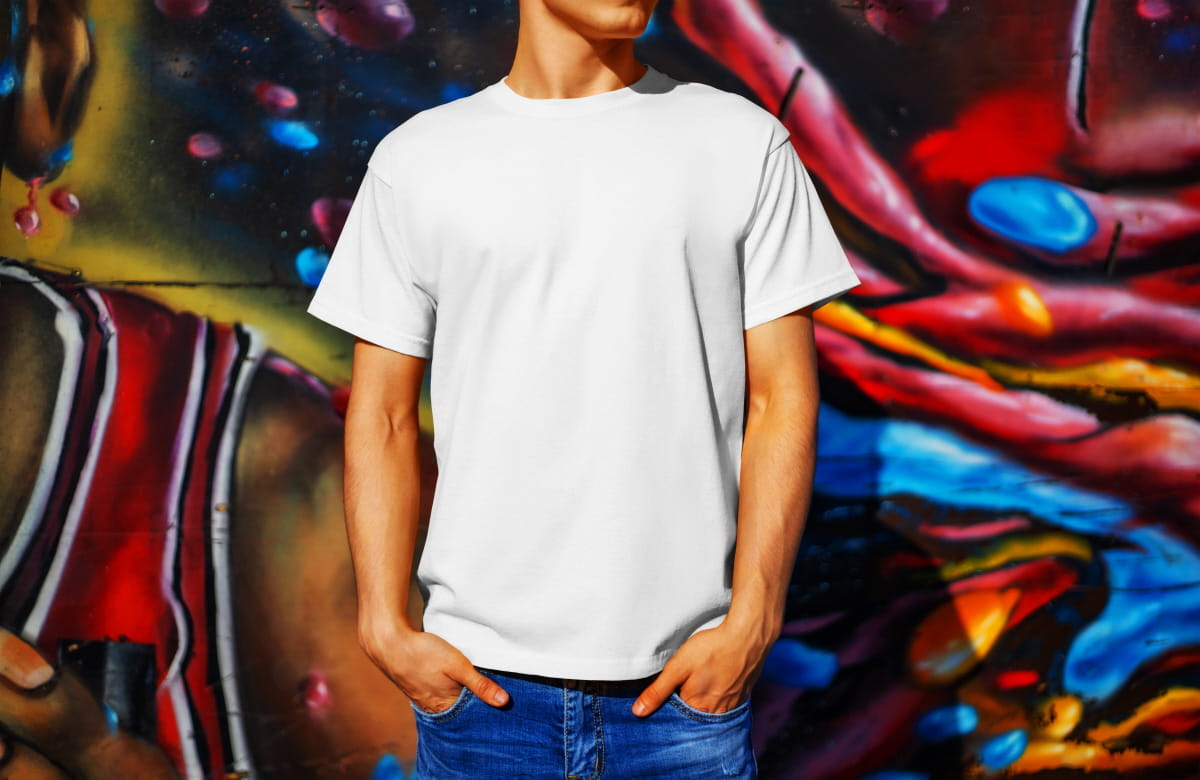 Template of a white T-shirt on a guy, against the background of a colorful wall, front view. Mockup clothing for presentation in the store. Design of casual clothes with a place for a pattern.